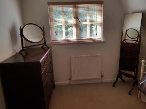 a bedroom with a dresser and a mirror on a dresser at Weir Cottage in Fordingbridge