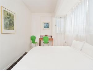 um quarto com uma cama branca e 2 cadeiras verdes em Cozy 1 BR Apt Only a 5 Minute Walk from the Beach by Sea N' Rent em Tel Aviv