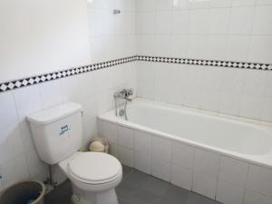 a white bathroom with a toilet and a bath tub at Admiral Villa in Carita