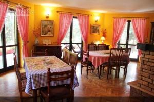 a dining room with a table and chairs and windows at Guest House Alpska Vila in Zlatibor