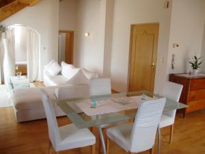- un salon avec une table en verre et des chaises blanches dans l'établissement Sonnenresidence Alpenhof, à Termeno