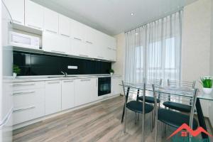 a kitchen with white cabinets and a glass table with chairs at Видовая на 25 этаже in Kyiv +8 photos