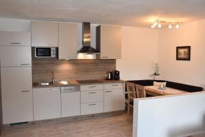 a kitchen with white cabinets and a wooden table at Haus Vlcek in Nauders