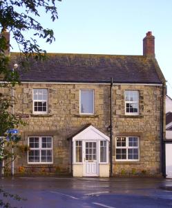 uma velha casa de tijolos com uma porta branca em Megstone House em Seahouses