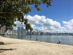 people on the beach with a city in the background at Apartamento Dante Tomio in Balneário Camboriú