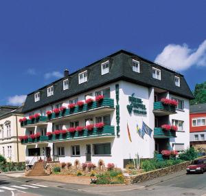 ein großes weißes Gebäude mit roten Blumen drauf in der Unterkunft Rheinhotel Rüdesheim - Wellness in Rüdesheim am Rhein