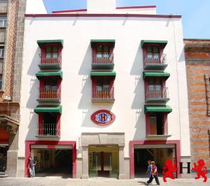un edificio bianco con finestre rosse e un orologio sopra di Hotel Leones a Puebla