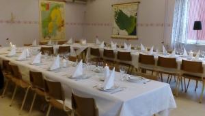 Gafsele Lappland Hostel في Väster Gafsele: غرفة بطاولات بيضاء وكراسي بمناديل بيضاء