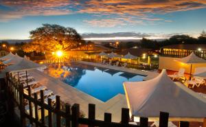 una gran piscina con sombrillas, mesas y sillas en Harmonie Hotel De Montaña - Adults only en Villa General Belgrano