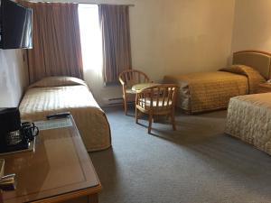 ein Hotelzimmer mit 2 Betten, einem Tisch und Stühlen in der Unterkunft Hotel Deoro in Lillooet