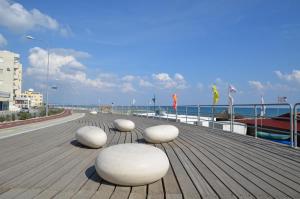 four white chairs sitting on a boardwalk near the ocean at Blu Studio on the Sea in Larnaka
