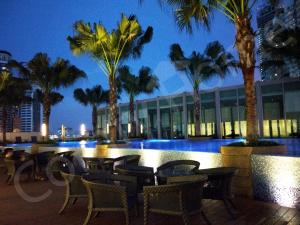 a resort with tables and chairs and palm trees at night at 5 STAR & LUXURY Apartment near KLCC/ KL City Centre in Kuala Lumpur