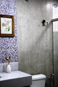 uma casa de banho com um chuveiro, um WC e uma fotografia em Chalé do Lago em Araxá