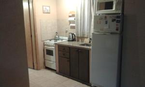 a small kitchen with a refrigerator and a microwave at Cabañas Los Aromos in Tandil