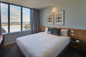 a hotel room with a large bed and a large window at Mantra Hotel at Sydney Airport in Sydney