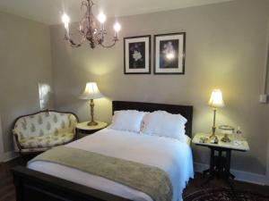 a bedroom with a bed and a chair and a chandelier at Concord Quarters in Natchez