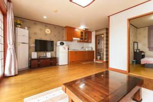 a large kitchen with a table and a refrigerator at Nuyoungnayoung Pension in Seogwipo