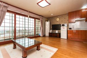 a large kitchen with a table and a refrigerator at Nuyoungnayoung Pension in Seogwipo