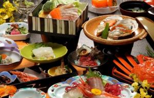 una tabella piena di diversi tipi di alimenti su piatti di Hotel Shiiya a Sado