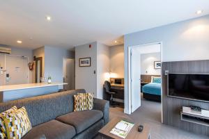 sala de estar con sofá y cama en Quest Newmarket Serviced Apartments, en Auckland