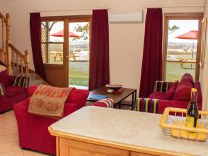 a living room with red chairs and a table at Berenbell Vineyard Retreat in Pokolbin