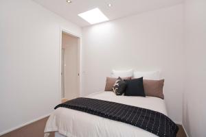 a white bedroom with a bed with pillows on it at Four Kings 3 in Anglesea