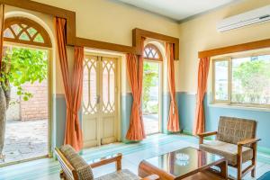 ein Wohnzimmer mit orangefarbenen Vorhängen sowie einem Tisch und Stühlen in der Unterkunft Hotel Inn Season in Jodhpur