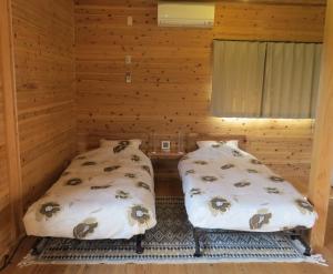 屋久島にあるコテージ オレンジハウス 屋久島のログキャビン内のベッド2台が備わる部屋です。