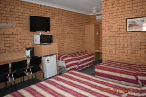 a room with two beds and a flat screen tv at Cooee Motel in Gilgandra