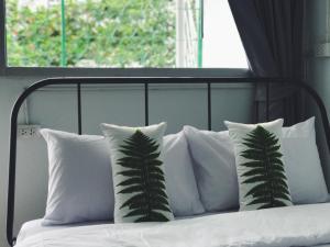 a bed with white pillows and a plant on it at Victory Park Hostel in Bangkok