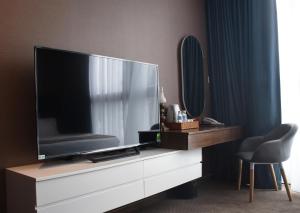 a living room with a large television on a dresser at Signature Boutique Hotel in Ho Chi Minh City