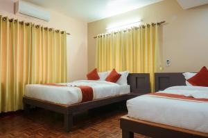 two beds in a room with yellow curtains at Sweet Dream Apartment in Kathmandu