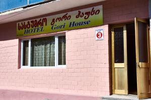 a pink brick building with a hotel car house at GoriHouse in Gori