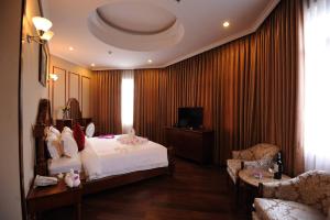 a bedroom with a bed and a couch and a tv at An Loc Hotel & Spa in Binh Long