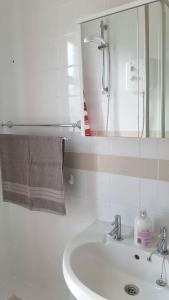 ein weißes Badezimmer mit einem Waschbecken und einem Spiegel in der Unterkunft Dumfries Central apartment in Dumfries