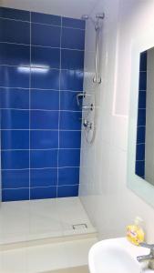 y baño con ducha y pared de azulejos azules. en Hostel Kwadrans, en Gliwice