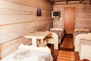 a room with a table and two beds and a tv at Tsisarske Urochyshe in Rozgirche