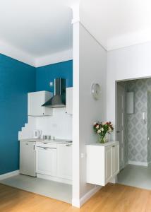 cocina con armarios blancos y paredes azules en Apartament Rozbrat en Varsovia