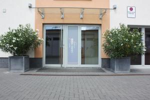 a glass door of a building with two potted plants at Hotel Grand Tour in Cologne