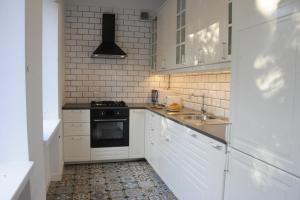 a white kitchen with a stove and a sink at MiłoTu - Apartament Marszałkowski in Warsaw