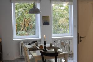 a dining room with a table and chairs and two windows at MiłoTu - Apartament Marszałkowski in Warsaw