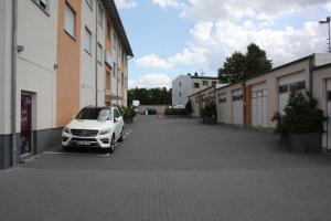 een witte auto geparkeerd op een parkeerplaats naast de gebouwen bij Hotel Grand Tour in Keulen