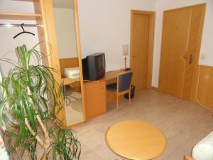 a room with a desk with a television and a table at Gasthof Sonne in Horriwil