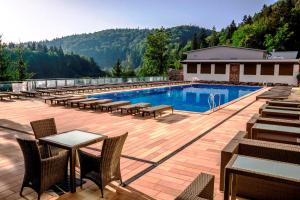 a swimming pool with tables and chairs on a patio at Stanislavsky Hotel Group in Yaremche