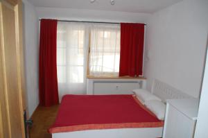 a bedroom with red curtains and a bed with a red blanket at Kronburger in Oberammergau