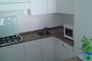 una cucina bianca con lavandino e forno a microonde di Appartamento Centromare solo famiglie a Lido di Jesolo