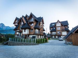 uma grande casa de madeira com telhado preto em TatryTop Apartamenty Szymaszkowa Ski Premium em Zakopane