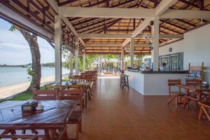 um restaurante com mesas e cadeiras de madeira e a praia em Samui Mermaid Beachfront em Bangrak Beach
