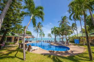 a resort swimming pool with palm trees and the ocean at Samui Mermaid Beachfront in Bang Rak Beach
