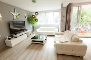 ein Wohnzimmer mit weißen Möbeln und einem TV in der Unterkunft Le Célestay in Villeurbanne
